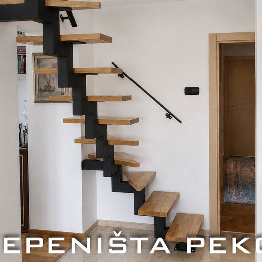 Crna kaskadna metalna konstrukcija stepenica sa svetlim drvenim gazištima montirana uz zid enterijera