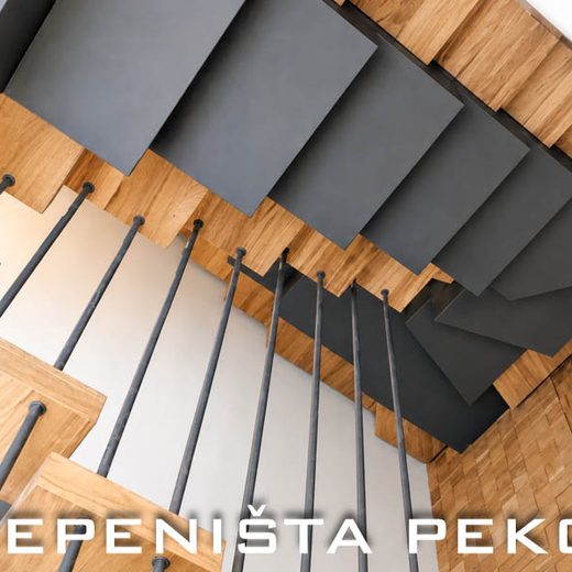 Perspektivni pogled odozdo na kaskadno obloženo stepenište u tamno sivoj boji sa vertikalnim ogradnim šipkama