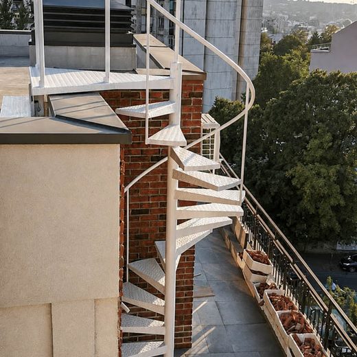 Bledo belo spoljno spiralno metalno stepenište od rebrastog lima za izlaz na krovnu terasu