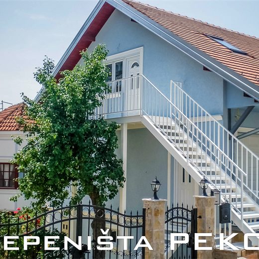 Bledo belo spoljno metalno stepenište sa podestom i zaštitnom ogradom za ulaz na sprat privatne kuće